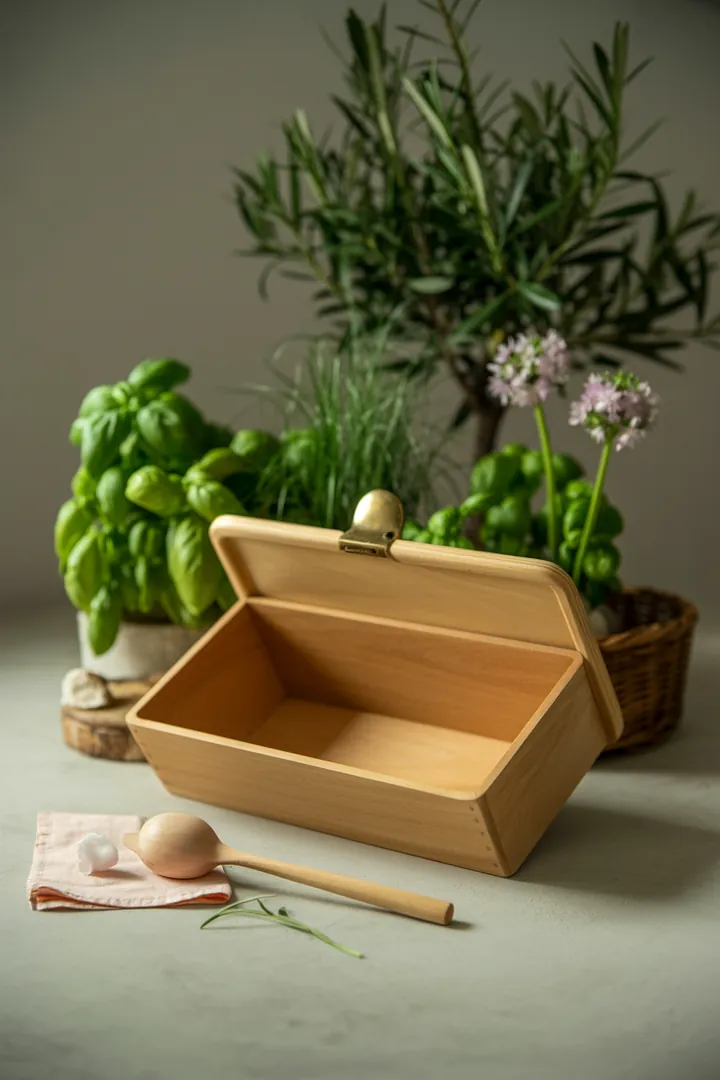 Ein gepflegter Aufbewahrungsbehälter für Brot wird mit einem sanften Essigreiniger und einer Bürste gereinigt, während ein Mikrofasertuch bereitliegt.